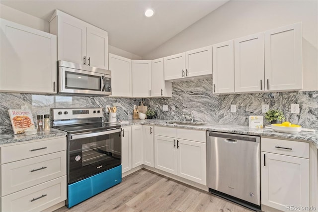 kitchen with backsplash, stainless steel appliances, vaulted ceiling, light hardwood / wood-style flooring, and white cabinets