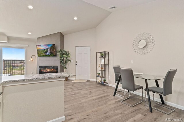 office featuring light hardwood / wood-style floors, lofted ceiling, and a fireplace