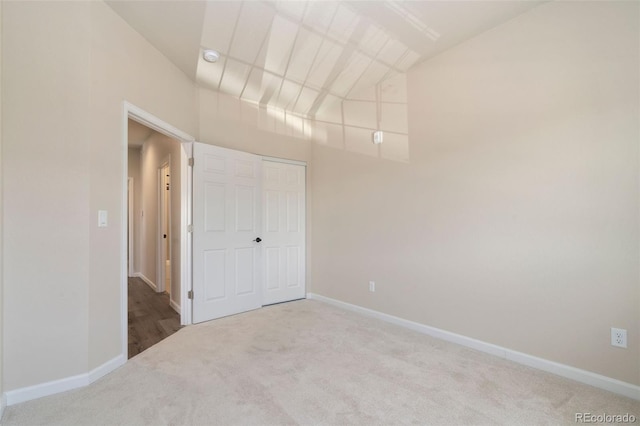 unfurnished bedroom with light colored carpet and a closet