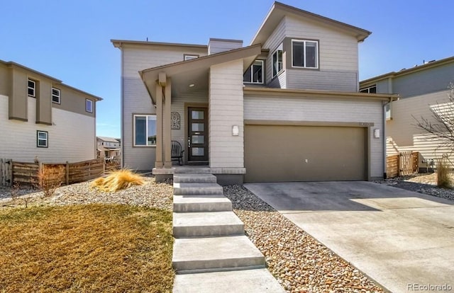 modern home featuring an attached garage, driveway, and fence