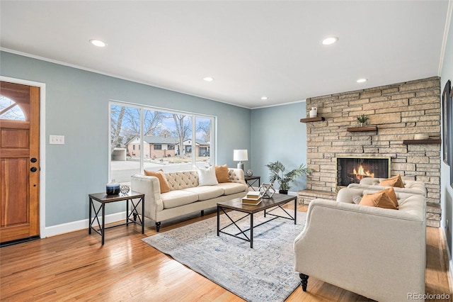 living room with ornamental molding, light wood-type flooring, a fireplace, and baseboards