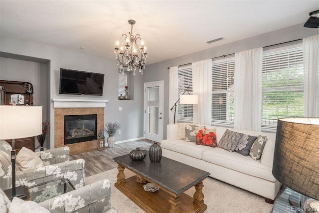 living room with hardwood / wood-style floors, a notable chandelier, and a fireplace