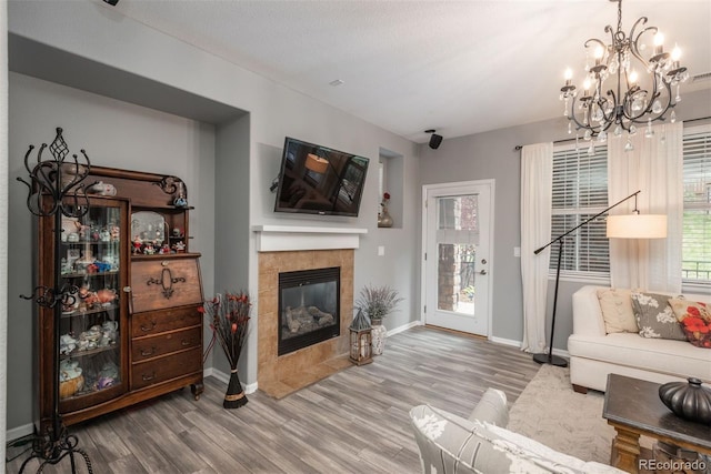 living room with a tile fireplace, wood-type flooring, plenty of natural light, and a notable chandelier