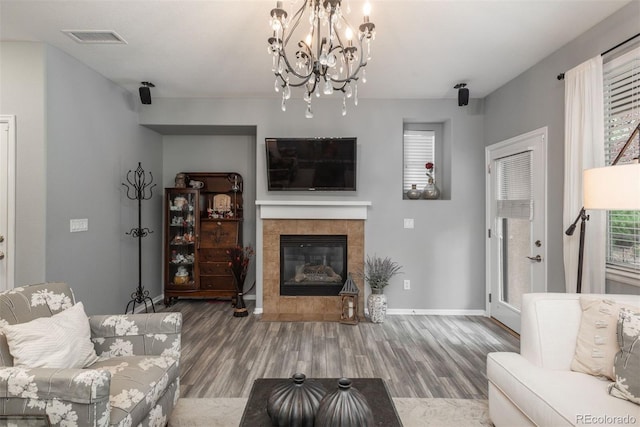 living room featuring hardwood / wood-style flooring, a notable chandelier, and a tile fireplace