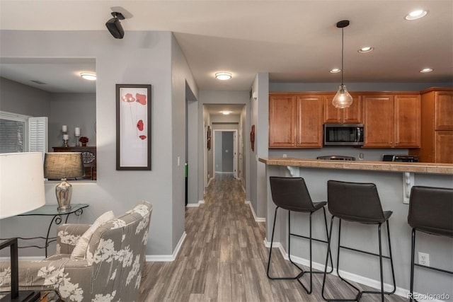 kitchen with decorative light fixtures, tile counters, hardwood / wood-style flooring, and a breakfast bar area