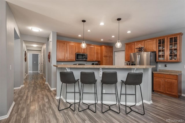 kitchen featuring pendant lighting, a breakfast bar, a center island, light hardwood / wood-style floors, and stainless steel appliances