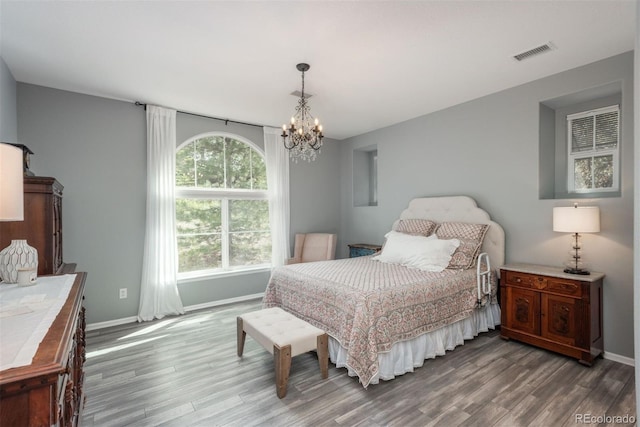 bedroom with wood-type flooring and a notable chandelier