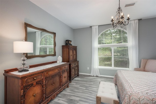 bedroom featuring a notable chandelier, light hardwood / wood-style flooring, and multiple windows