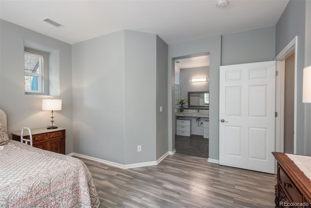 bedroom featuring ensuite bath and hardwood / wood-style flooring