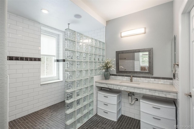 bathroom featuring sink, tile patterned flooring, tiled shower, tile walls, and a healthy amount of sunlight