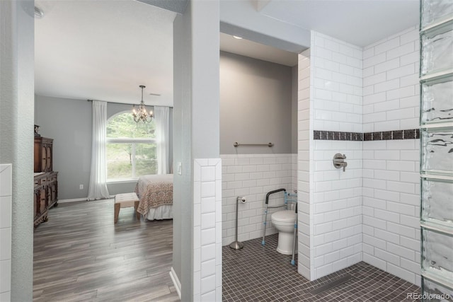 bathroom with hardwood / wood-style flooring, toilet, tile walls, a tile shower, and a chandelier