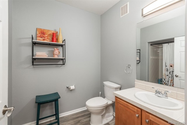 bathroom with a shower with shower curtain, hardwood / wood-style floors, vanity, and toilet