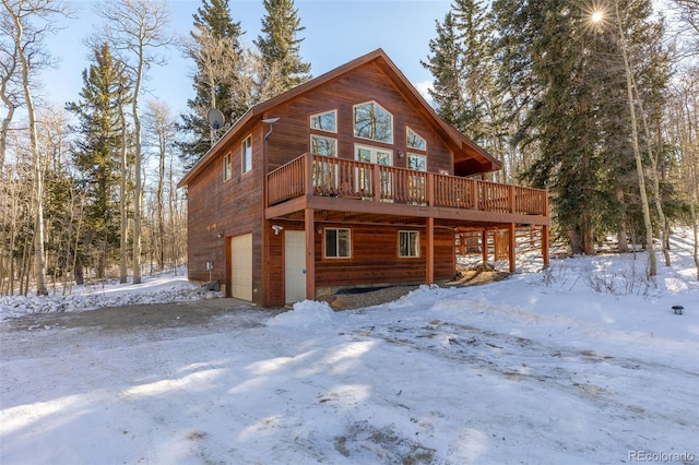 snow covered property featuring a garage and a wooden deck