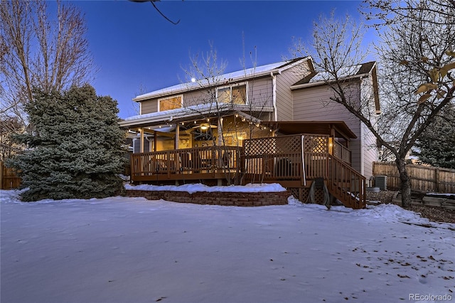 snow covered house with central AC unit and a wooden deck