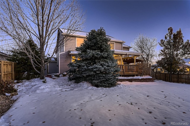 snow covered back of property with a wooden deck