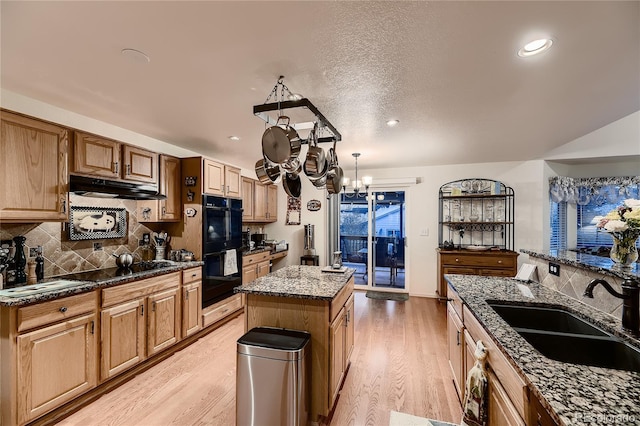 kitchen with black appliances, sink, an inviting chandelier, light hardwood / wood-style flooring, and a center island