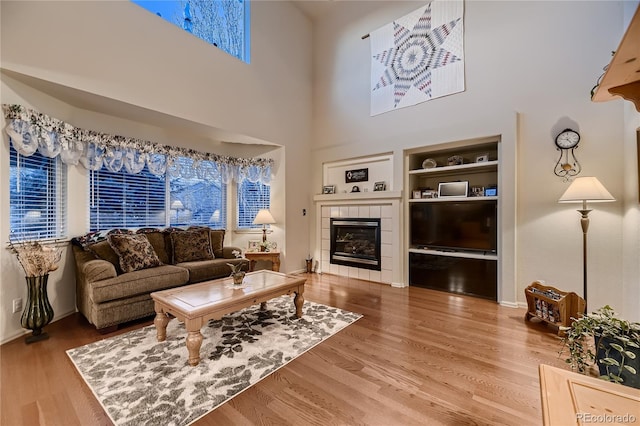 living room with hardwood / wood-style flooring, built in features, and a tiled fireplace