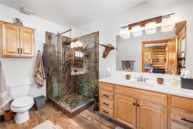 bathroom featuring toilet, rustic walls, a shower with shower door, vanity, and hardwood / wood-style flooring