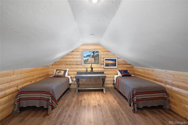 bedroom featuring lofted ceiling, hardwood / wood-style floors, rustic walls, and a textured ceiling