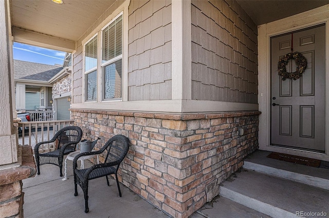 property entrance featuring covered porch and roof with shingles