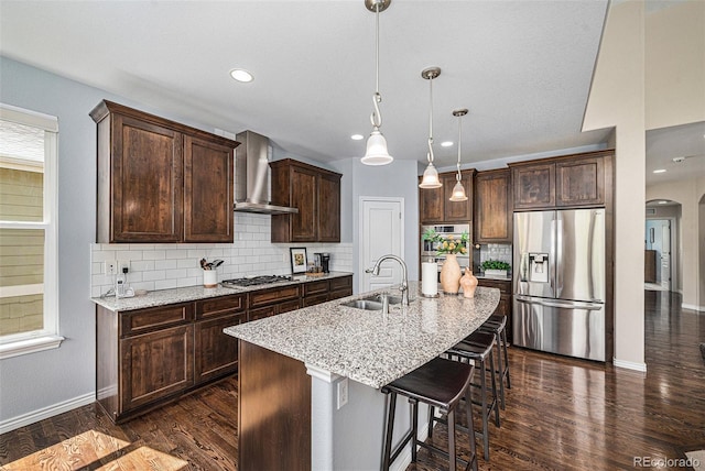 13942 W 87th Dr, Arvada, CO 80005 - kitchen featuring appliances with stainless steel finishes, a sink, wall chimney range hood, arched walkways, and baseboards