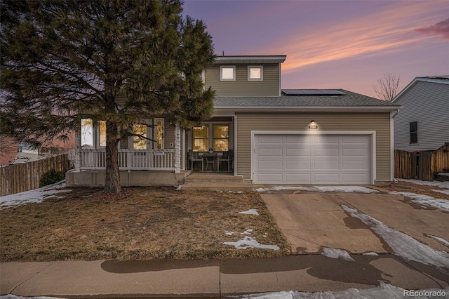 view of front of home featuring covered porch, solar panels, and a garage