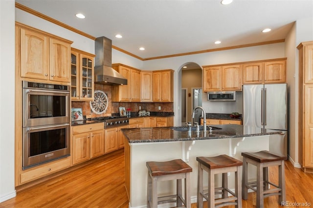 2105 Baguette Dr, Castle Rock, CO 80108 - kitchen with stainless steel appliances, wall chimney range hood, light wood-style floors, recessed lighting, and a breakfast bar