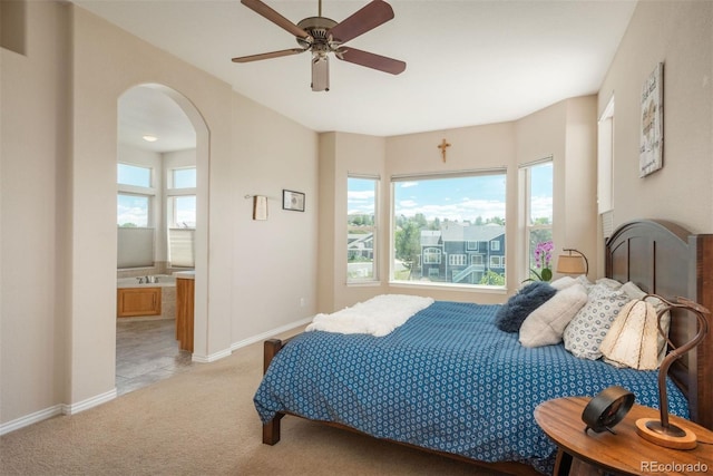 2105 Baguette Dr, Castle Rock, CO 80108 - bedroom with arched walkways, light carpet, ensuite bath, and a ceiling fan
