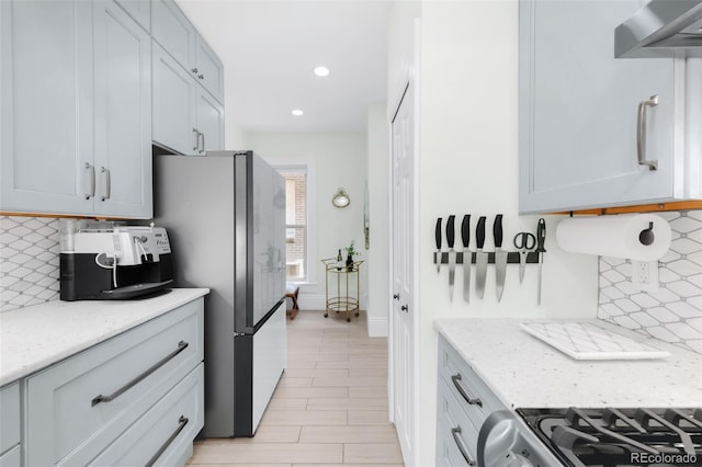 3147 Vallejo St, Denver, CO 80211 - kitchen with wall chimney range hood, tasteful backsplash, light stone countertops, recessed lighting, and freestanding refrigerator