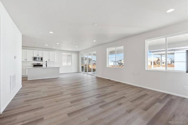 unfurnished living room with sink and light wood-type flooring