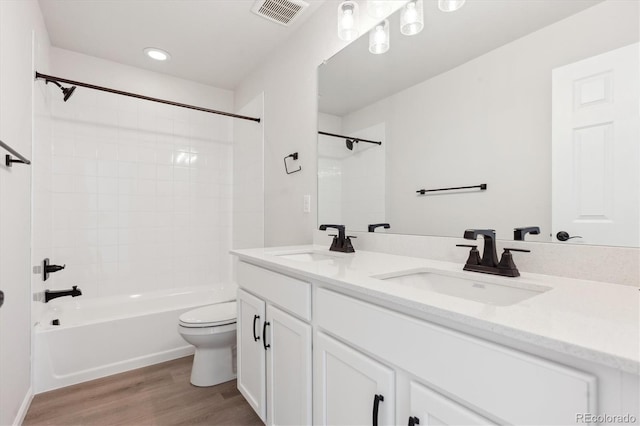 full bathroom featuring wood-type flooring, tiled shower / bath, vanity, and toilet