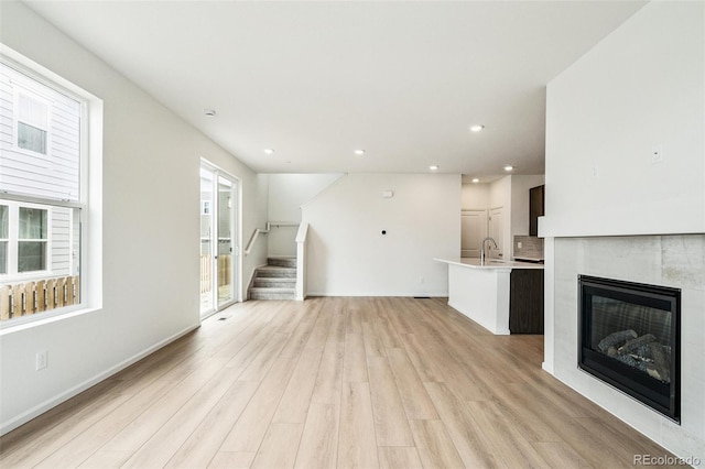 13568 E 111th Ave, Commerce City, CO 80022 - unfurnished living room featuring light wood finished floors, stairs, recessed lighting, and a tiled fireplace