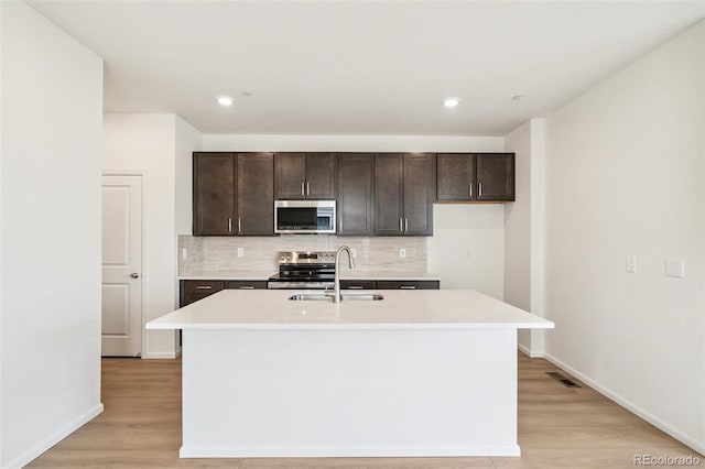 13568 E 111th Ave, Commerce City, CO 80022 - kitchen featuring tasteful backsplash, light wood finished floors, appliances with stainless steel finishes, dark brown cabinets, and recessed lighting