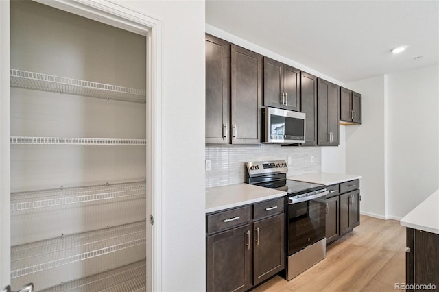13568 E 111th Ave, Commerce City, CO 80022 - kitchen featuring stainless steel appliances, dark brown cabinets, light wood-type flooring, light countertops, and decorative backsplash