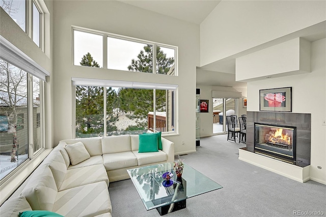 living room featuring a high ceiling, carpet flooring, and a tile fireplace