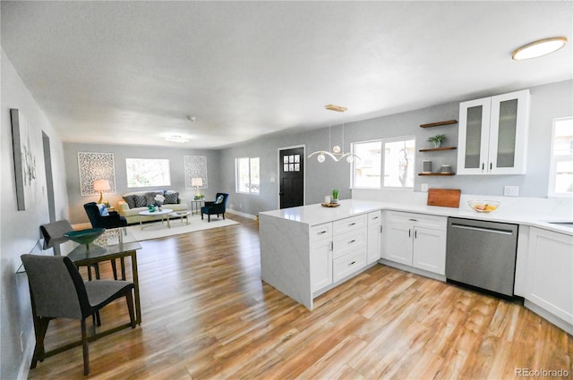 kitchen featuring open floor plan, a peninsula, stainless steel dishwasher, and white cabinets