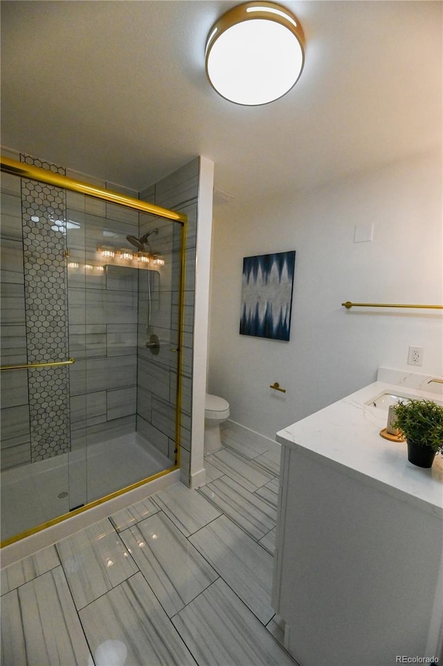 full bathroom featuring a stall shower, vanity, toilet, and baseboards