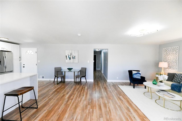 living area with baseboards, visible vents, and light wood-style floors
