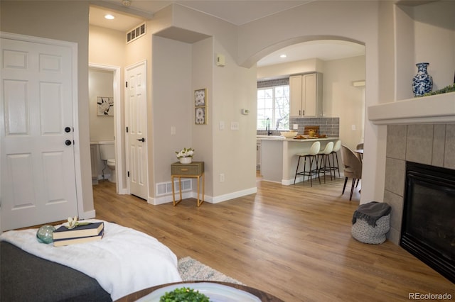 6845 S Webster St Unit E, Littleton, CO 80128 - living area featuring arched walkways, light wood-style floors, a tiled fireplace, and recessed lighting