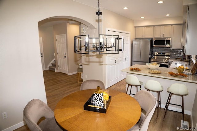 6845 S Webster St Unit E, Littleton, CO 80128 - dining room with arched walkways, light wood-type flooring, a chandelier, recessed lighting, and stairs