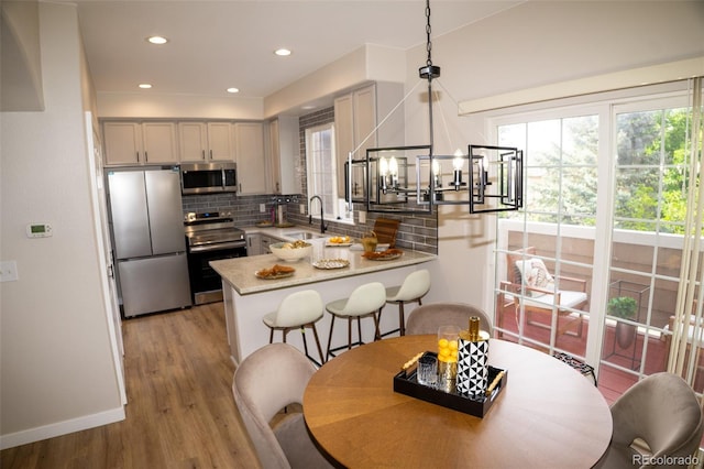 6845 S Webster St Unit E, Littleton, CO 80128 - kitchen with appliances with stainless steel finishes, a peninsula, healthy amount of natural light, tasteful backsplash, and recessed lighting