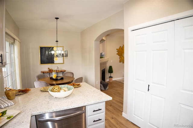 6845 S Webster St Unit E, Littleton, CO 80128 - kitchen with dishwasher, arched walkways, light wood-style flooring, light stone counters, and a chandelier