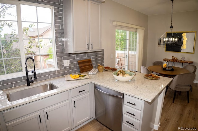 6845 S Webster St Unit E, Littleton, CO 80128 - kitchen featuring dishwasher, a peninsula, wood finished floors, backsplash, and a chandelier