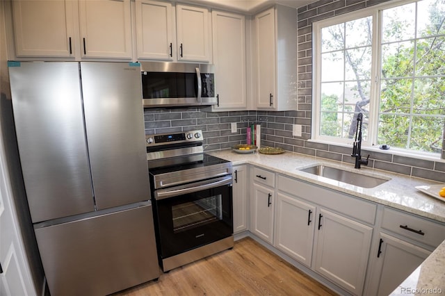 6845 S Webster St Unit E, Littleton, CO 80128 - kitchen featuring stainless steel appliances, tasteful backsplash, light wood-style flooring, and light stone countertops