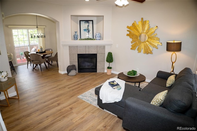 6845 S Webster St Unit E, Littleton, CO 80128 - living room with arched walkways, wood finished floors, a tile fireplace, and a chandelier