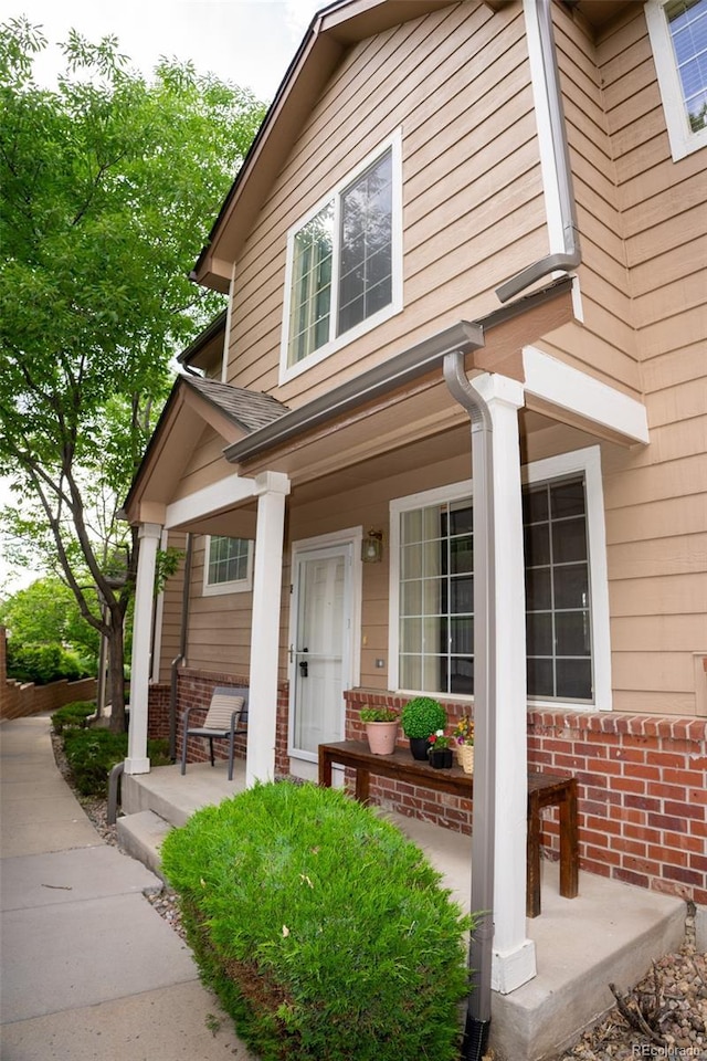 6845 S Webster St Unit E, Littleton, CO 80128 - doorway to property featuring covered porch and brick siding