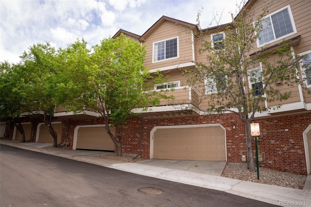 6845 S Webster St Unit E, Littleton, CO 80128 - view of front of house with a garage, brick siding, and concrete driveway