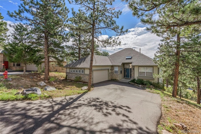 view of front of house with aphalt driveway, stone siding, and an attached garage