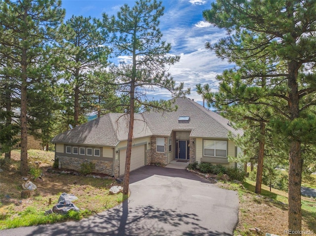 view of front facade featuring a garage, stone siding, a shingled roof, and aphalt driveway