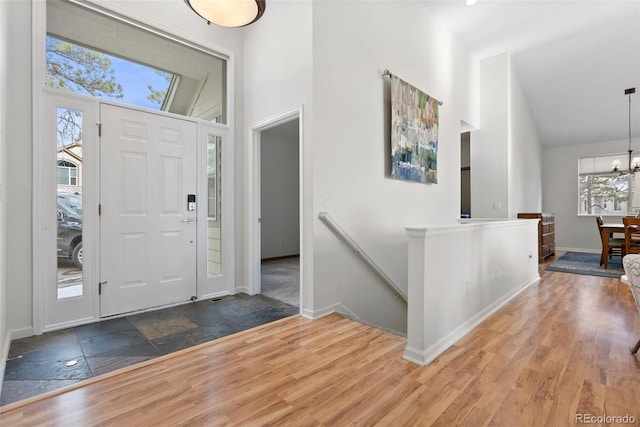 entrance foyer with an inviting chandelier, baseboards, high vaulted ceiling, and wood finished floors